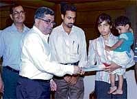 Rita Menezes, wife of ill-fated passenger of Air India Express Melwin Kiran Menezes, receiving the compensation cheque of Rs 10 lakh from Air India Executive Director (Southern  Region) Sunil Kishan in Mangalore on Friday. DH Photo