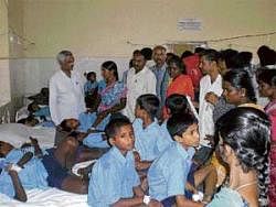 PLAN GONE AWRY? Block Education Officer Jairaj inquiring about the health of students in government hospital, KGF on Tuesday. DH Photo