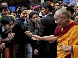 Tibetan spiritual leader the Dalai Lama is greeted by people as he walks to watch an exhibition of traditional Tibetan paintings in Dharamsala on Tuesday. The Dalai Lama turned 75 on Tuesday. PTI