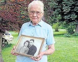 Jean Stevens, 91, holds a photograph from the 1940s of  herself and her late husband, James, outside her home. AP