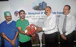 A J Hospital Chairman A J Shetty handing over bouquet to Umar Farooq Mohammed, one of the survivors of May 22 Air India Express mishap, in Mangalore on Tuesday. DH Photo