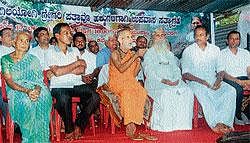 Pejawar seer Vishweshatheertha Swamiji participating in the protest to show solidarity to Gregory Patrao and family, outside Deputy Commissioners office on Thursday. Mary Patrao, mother of Gregory Patrao, Gregory Patrao, Kannada Sahithya Academy former state president HArikrishna Punaroor, Fr William Martis among others look on. DH Photo