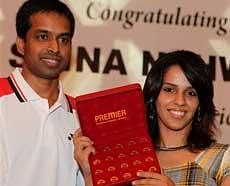 World No. 3 badminton player Saina Nehwal, who is 20, poses with twenty 24-carat gold coins, during a felicitation function in New Delhi on Tuesday. Her coach Pullela Gopichand is also seen. PTI