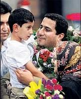 Shahram Amiri holds his son as he arrives at the Imam Khomeini airport outside Tehran on Thursday. AP