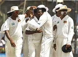 Sri Lankan bowler Muttiah Muralitharan, center is congratulated by teammates after he claimed five wickets in an inning during the first test cricket match against India in Galle, Sri Lanka, Wednesday. AP