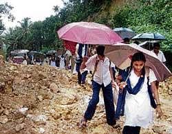 Through the debris: Students negotiating a road blocked by a landslide at Kadengodlu Onibagilu in Peruvai near Vittal in Bantwal taluk, on Wednesday.  dh photo
