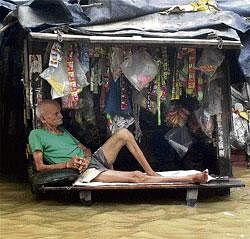 Out of business: A shopkeeper takes a rest at his flooded shop in Pilibhit district, Uttar Pradesh, on Friday. PTI