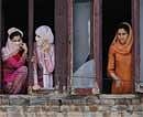 Kashmiri  women watch from the windows of their house funeral procession of Tanveer Ahmed in Pampore, outskirts of Srinagar on Sunday. AP