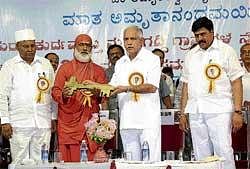 Trusts contribution: Chief Minister B S Yeddyurappa receives the symbolic key to 242 houses built for flood victims at Donga Rampur by Mata Amritanandamayi Trust at a  programme organised in Raichur on Wednesday. DH Photo