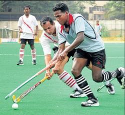 Praful K (right) of MLI tries to tackle Tanu Nanjappa of RBI in the Travancore Cup hockey meet. DH photo