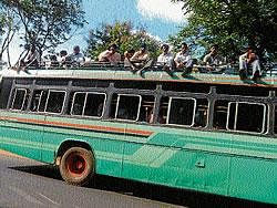 Villagers travelling atop a private bus, towards Mysore on Suttur- T Narsipur Road on Tuesday. DH PHOTO