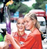 Pole vault champion Yelena Isinbayeva (left) hands over the Youth Olympic Games torch to Singapore student Karin Biese in Singapore on Friday. AP