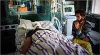 Losing Hope: Aabid Nabi sat next to his brother Fida Nabi in a hospital in Srinagar. NYT