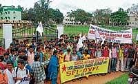 Students of Government Independent PU College holding a protest in front of land sanctioned for the construction of college, in Hassan on Tuesday.  dh photo