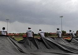 Sri Lankan ground staff pull covers into the field as rain clouds loom over the stadium before the start of the tri series one day international cricket match between Sri Lanka and New Zealand in Dambulla. AP