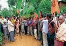 BJP workers staging a protest by planting banana plants on Baradi road, demanding water supply and repair of road at Nellyahudikeri on Sunday.  DH Photo
