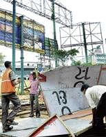 At Last: BBMP workers bringing down unauthorised advertisement hoardings and boards at the Brigade Road in the City on Friday. DH Photo