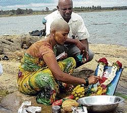 right TO RITE: Kamala, who tonsured her head performs last rites of her mother on the banks of Mallaghatta tank in Turuvekere on Sunday. DH Photo