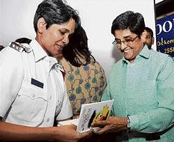 Former super cop Kiran Bedi signing the book Broom & Groom for police officer Geetha Kulkarni, during its release at Strand Book Stall in Bangalore on Tuesday. dh photo