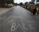 Kashmiri women walk past a graffiti on a road during a curfew on the outskirts of Srinagar, India on Sunday. AP Photo