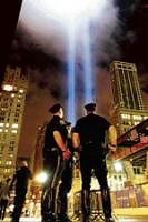 In remembrance: Officers are seen in the backdrop of the Tribute in Light as it rises above New York on Saturday. In an annual tradition, the two bright blue beams rise from lower Manhattan in memory of the fallen twin towers. AP