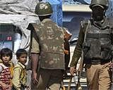Children look at paramilitary soldiers urging civilians to stay indoors during curfew in Srinagar on Friday. AP