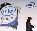 A woman checks her mobile phone as she walks past an Intel Core Duo advertisement outside a computer shop in Beijing March 26, 2007.Reuters File