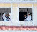 Study-time again: Students look down from a school building in curfew-bound Srinagar on Monday. AFP