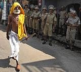 A Hindu holyman walks past Indian securitymen standing guard in Ayodhya, AP