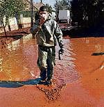 A Hungarian firefighter walks through a street flooded by toxic red sludge. AP