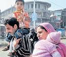 A couple walks carrying their children as they look for transport during a separatist-sponsored general strike in Srinagar on Wednesday. PTI