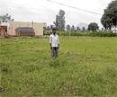 No hope: A farmer stands in his field at Yaluvahalli, that has been acquired by the district administration for widening of  National Highway 7. DH Photo
