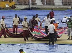 Workers cover the pitch with rugs after heavy rains ahead of the third and last one day international cricket match between India and Australia in Goa on Saturday, AP