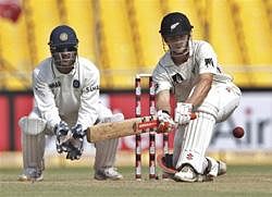 India's captain Mahendra Singh Dhoni, left, watches as New Zealand's Kane Williamson plays a shot during the fourth day of their first cricket test match in Ahmadabad, India, Sunday, Nov. 7, 2010. (AP Photo/Aijaz Rahi)