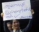 Myanmar's pro-democracy leader Aung San Suu Kyi displays a placard that reads, ''I also Love the People,'' to her supporters at the headquarters of her National League for Democracy Party on Sunday  in Yangon, Myanmar. AP