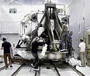High-energy experiment : A crew works on the Alpha Magnetic Spectrometer at CERN in Geneva.  (Fred Merz/ New York Times).