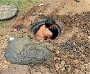 A pourakarmika cleaning a chocked manhole at Shankaranagar in Mandya, without any safety measures. DH PHOTO