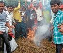 ANgry:Protesters burning tobacco at Ramanathapurin Hassan district on Tuesday.  DH photo
