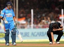 Indian cricketer Gautam Gambhir (L) looks on as New Zealand cricketer Kyle Mills reacts after being hit for a boundary by Gambhir during the third One Day International (ODI) match between India and New Zealand at the Reliance stadium in Vadodara . . AFP