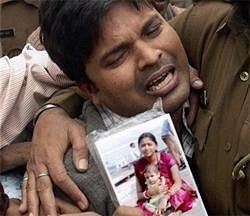Santosh Kumar Sharma cries with a picture of his 1-yr-old daughter Swastika who died in Tuesday's explosion at Dashashwamedh Ghat, in Varanasi on Wednesday. PTI
