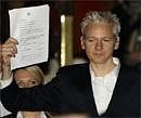 WikiLeaks founder Julian Assange holds up a court document for the media after he was released on bail, outside the High Court, London on Thursday. AP photo
