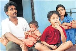 In the grip of nightmare: Firan Kumar Jha, Anjali Jha, Pankaj and Neeraj (on Firans lap) sitting outside their home near Yeyyadi in Mangalore on Saturday. DH Photo