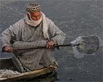 A Kashmiri boatman breaks the frozen surface of water to make way through the Dal Lake in Srinagar on Monday. AP