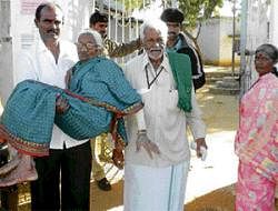 A resident of Manchanahalli carries Achamma (106) to a voting booth in Chikkaballapur taluk on Sunday. DH Photo