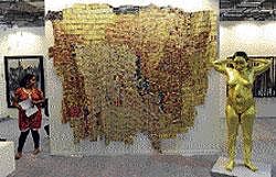 A visitor looks at works by artists Ghana El Anatsui and Ravender Reddy (R) at Sakshi Gallery during the Indian Art Summit in New Delhi on Friday. AFP