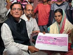In this July 31, 2008 file photo, Sulah founder Bindeshwar Pathak hands over Rs 3 lakh draft to Kalavati, whose name was mentioned by AICC General Secretary during his speech in Parliament, at her village Jalka, about 120 km away from Nagpur. PTI