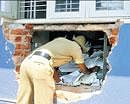 A constable looks inside the broken wall of Vijaya Bank on Thursday night at Chikkajala in Bangalore on  Friday. DH photo/ B K Janardhan