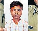 A police officer shows a picture of Anand, accused of killing three persons, in Bangalore on Saturday. DH&#8200;Photo