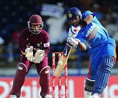 Indian batsman Virat Kohli plays a shot in front of West Indies wicketkeeper Carlton Baugh during the second ODI between West Indies and India at the Queen's Park Oval in Port of Spain. AFP