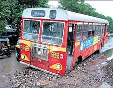 Raining misery: A bus is stuck in a ditch following heavy rain in Thane on Friday. PTI
